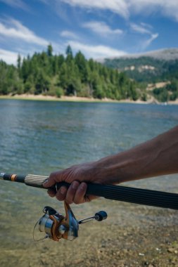 Olta kamışı tekeri yaklaşıyor, arkasında güzel bir gündoğumu olan bir adam balık tutuyor. ABD
