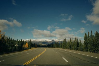 Güneşli ve bulutlu bir günde Alaska Hwy 'de Manzaralı Yol. Arka plandaki dağlar. Yüksek kalite fotoğraf