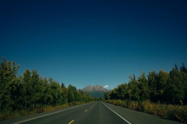 Güneşli ve bulutlu bir günde Alaska Hwy 'de Manzaralı Yol. Arka plandaki dağlar. Yüksek kalite fotoğraf