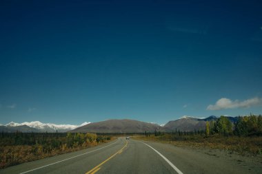 Güneşli ve bulutlu bir günde Alaska Hwy 'de Manzaralı Yol. Arka plandaki dağlar. Yüksek kalite fotoğraf