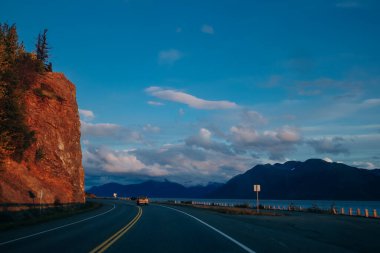 Scenic Route, Alaska Hwy, during a sunny and cloudy day. Mountains in Background. High quality photo clipart