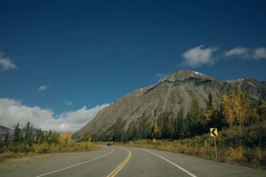 Scenic Route, Alaska Hwy, during a sunny and cloudy day. Mountains in Background. High quality photo clipart