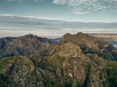 Güneşin ilk ışınlarının muhteşem doğal topoğrafyayı aydınlatan altın bir parıltıyla madeira dağlarının engebeli zirvelerini çarpıcı bir şekilde görüntülemesi. Yüksek kalite fotoğraf