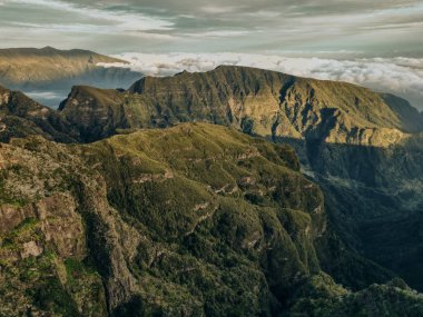 Güneşin ilk ışınlarının muhteşem doğal topoğrafyayı aydınlatan altın bir parıltıyla madeira dağlarının engebeli zirvelerini çarpıcı bir şekilde görüntülemesi. Yüksek kalite fotoğraf
