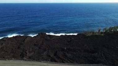 Okyanus dalgaları Hawaii 'de siyah bir bazalt kayaya vuruyor. Yüksek kalite 4k görüntü