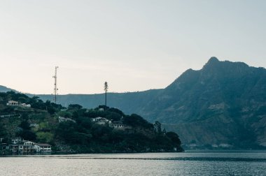 Atitlan Gölü 'nde sakin bir sabah. Guatemala' da dağlarla çevrili bir tekne ve göl kenarında bir kulübe var. Yüksek kalite fotoğraf