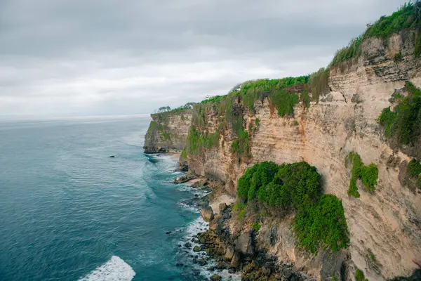 Panorama Okyanus Kıyısı 'na bak, Cliff. Gün batımı. Bali. Çiçek ve yeşil başlıklı dikey uçurum Hint Okyanusu 'nun üzerinde bunaltıcı bir manzara. Yüksek kalite fotoğraf