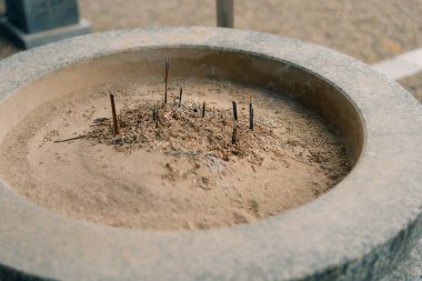 Shikoku, Japonya - 3 Ağustos 2025 Küller ve tütsü kalıntılarıyla dolu bir taş kase. Yüksek kalite fotoğraf