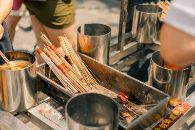 Pekin, Çin - 23 Haziran 2025 Ziyaretçiler bir tapınaktaki açık hava tütsü istasyonunda tütsü çubukları yakıyorlar. Yüksek kalite fotoğraf