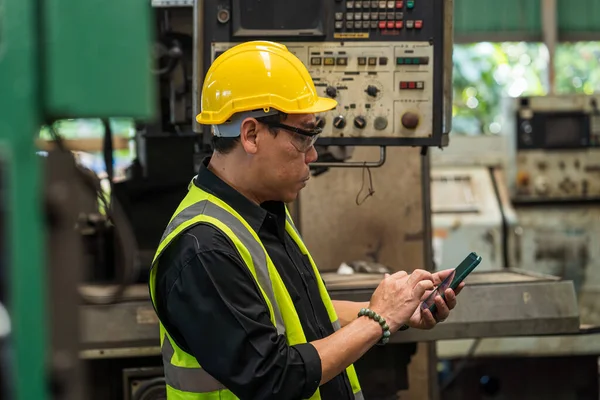 手机工程师 男技术员在一家钢铁厂工作 钢制机器上戴安全帽的男工 — 图库照片