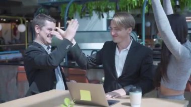 İş adamları, Ortak Çalışma Alanındaki başarılı bir proje için heyecanlandılar. Açık uzay ofisinde dizüstü bilgisayarda çalışan heyecanlı iş adamları.
