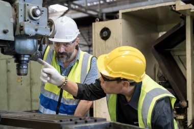 Personel ya da teknisyenler eski makinenin işleyişini uzaktan kontrol ediyorlar. Güvenlik kasklı bir işçi çelik makinesinde çalışıyor..