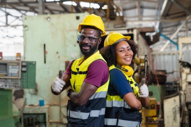 Endüstriyel bir fabrikada mühendis ya da profesyonel bir baş parmak. Genç bir mühendis başparmağını gösteren bir güvenlik kaskı takıyor..