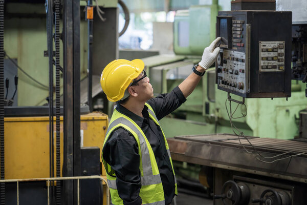 Staff or technicians are checking the operation of the old machine. Factory worker or engineer doing machine job in adept manufacturing workshop.
