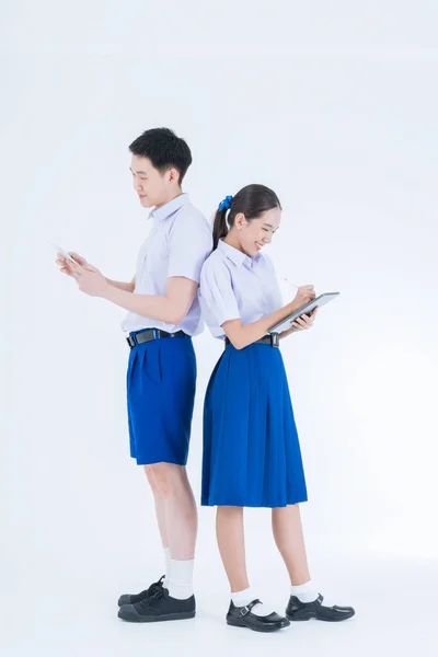 男孩和女孩在白色背景上使用平板电脑 身穿白底校服的亚洲女孩和男孩 泰国学生 — 图库照片