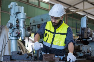 Teknisyen adam çelik fabrikasında çalışıyor. Güvenlik kasklı bir işçi çelik makinesinde çalışıyor..