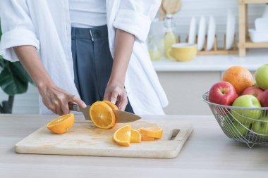 Vejetaryen yemeği pişirmek. Şef salata süslemek için portakal kesiyor. Bir kadın tahta kesme tahtasıyla portakal kesiyor..