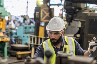 Teknisyen çelik fabrikasında çalışıyor. Koruyucu giysiler giyen işçiler çelik fabrikasında ağır makineler kullanıyorlar..