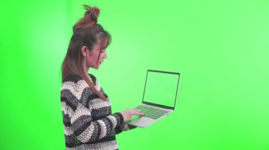 Dizüstü bilgisayar kullanan bir kadın. Yeşil ekran arka planındaki genç kadın.