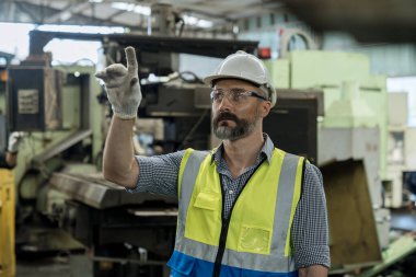 Güvenlik kasklı bir işçi çelik makine üzerinde çalışıyor. İşçi değirmenci endüstriyel üretim fabrikasında fabrika işletiyor..