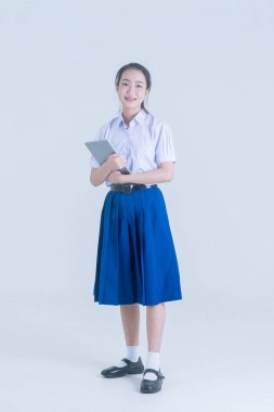 Asyalı güzel kız elinde tablet tutuyor. Beyaz arka planda mutlu lise öğrencisi.