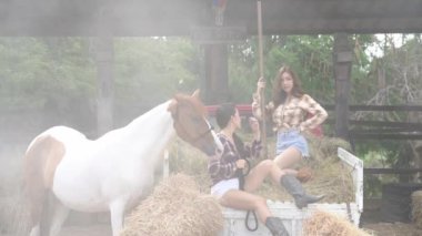 Genç kadın ve at dışarıda. Çiçekler ve atlarla yerde oturan kız..