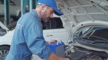 Araba tamircisi araba elektriği için yedek akü taşır. Araba aküsü değiştirme.