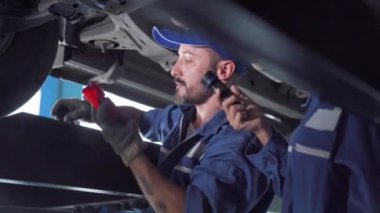Araba tamircisi, araç motoru tamiri. Üniformalı tamirci araba servisinde araba tamir ediyor..