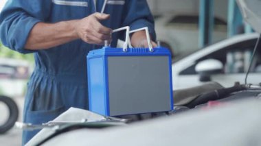 Araba tamircisi araba elektriği için yedek akü taşır. Araba aküsü değiştirme.