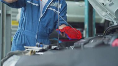Tamirci motor yağını kontrol ediyor. Tamirci bir araba atölyesinde yağ seviyesini kontrol ediyor..