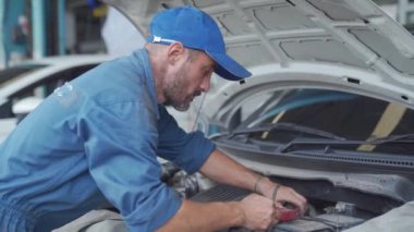 Profesyonel tamirci, müşteri arabasının elektrik sistemini tamir için getiriyor. Araba tamircisi yedek araba aküsü taşıyor..