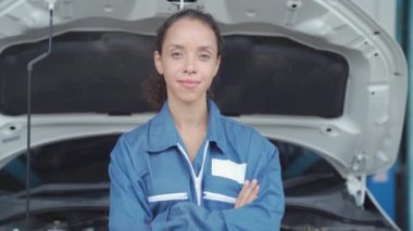 Tamirci motor yağını kontrol ediyor. Araç servisi bakım görevlisi Asyalı kadın garajda araç durumunu kontrol ediyor..