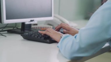 Bir ofis çalışanı bilgisayar klavyesine yazı yazıyor. İş kadını parlak ofisinde klavyesine yazı yazıyor.