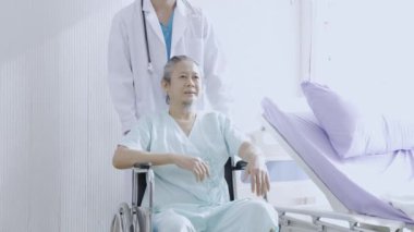 Koruyucu kıyafetli doktor yaşlı bir adamı itiyor. Doktor yardımı ve bakımı Asyalı kıdemli ya da yaşlı adam.