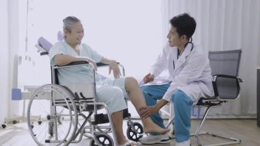 Doktor, hastanede dizinde yara izi olan Asyalı yaşlı bir hastayı kontrol ediyor. Nörolog, çekiç kullanan bir hastada diz refleksini test ediyor..