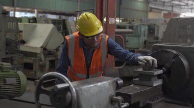 Üretim ekipmanları. Üniformalı ve kasklı Turner torna tezgahında çalışıyor..