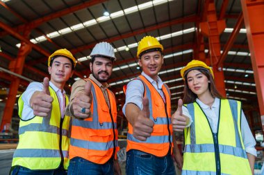 Takım mühendisi fabrikada çok çalışıyor. Başparmaklarını kaldırıp kameraya bakıyorlar..
