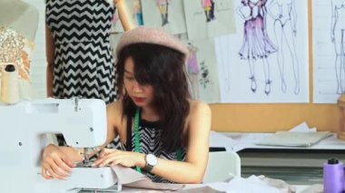 Terzi kadın elbise dikiyor. Çalışırken dikiş diken genç bir kadın..