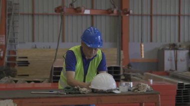  İşçiler sanayide şapka takıp şemaları gözden geçiriyorlar. Kasklı ve kasklı bir işçi..