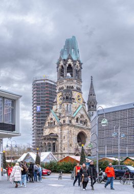 Berlin, Germany - December 31, 2022: Colourful holiday Christmas market in Berlin and a Gedchtniskirche, Kaiser Wilhelm Memorial Church. People celebrating the New Year Eve