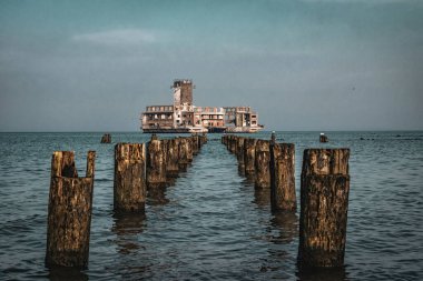 Old ruined wooden pier and a sandy beach