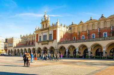 Krakow Polonya - 12 Kasım 2022: Krakow 'daki tarihi Pazar Meydanı. Piyasa binası ve yürüyen turistler, ünlü simge.