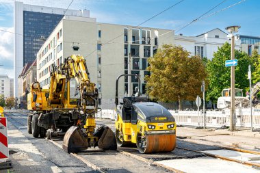 Berlin, Almanya - 25 Eylül 2022: Berlin şehir merkezindeki caddede sarı kazıcı ve yol yapım ekipmanları. Almanya 'da yol yapımı ve yenilenmesi