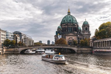 Berlin, Almanya - 25 Eylül 2022: Berlin 'deki tarihi bölgenin manzarası. Evanjelik Yüksek Kilise ve Kolej Kilisesi, Müze Adası ve Spree Nehri 'nde bir eğlence teknesi.