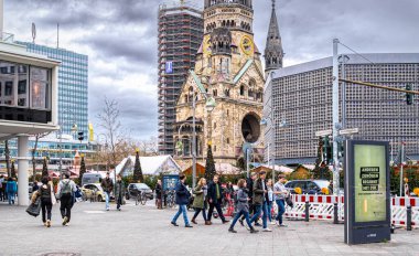 Berlin, Germany - December 31, 2022: Colourful holiday Christmas market in Berlin and a Gedchtniskirche, Kaiser Wilhelm Memorial Church. People celebrating the New Year Eve