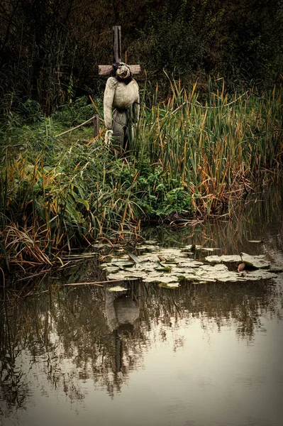 Scary garden scarecrow and mysterious pond