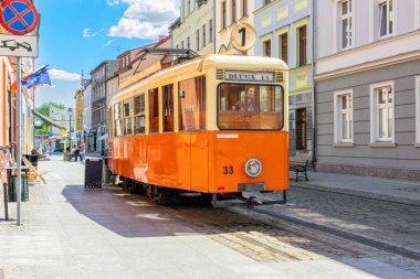 Bydgoszcz, Polonya - 13 Haziran 2023: Bydgoszcz tarihi bölgesinde caddede klasik sarı tramvay. Güneşli şehir manzarası ve güzel kaldırım kafesi
