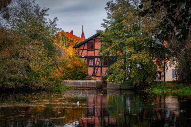 Güzel eski tuğla su değirmeni ve gölet. Sarı ve kırmızı yapraklı sonbahar kırsalları