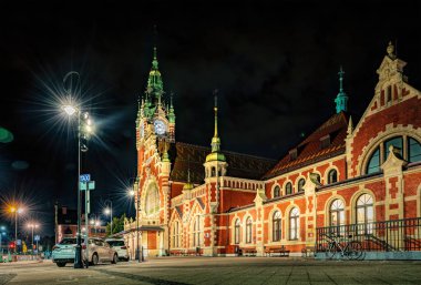 Gdansk, Polonya - 07 Ekim 2024: Gdansk 'taki tren istasyonunun tarihi tuğlaları ve bir saat kulesi. Gece kenti sokağı