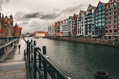 Gdansk, Polonya - 17 Kasım 2024: Gdansk 'ın tarihi simgesi, ortaçağ tuğlalı gotik evleri ve Motlawa nehrinin seti üzerinde modern apartman inşaatı. Dramatik yağmurlu sonbahar gökyüzü